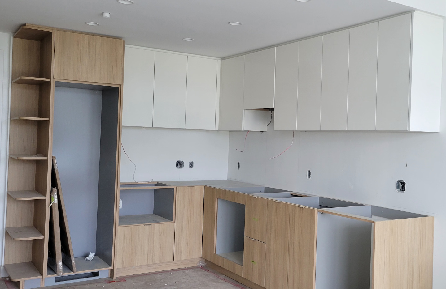 A kitchen under renovation, with newly installed cabinets, and kitchen counters currently being installed.