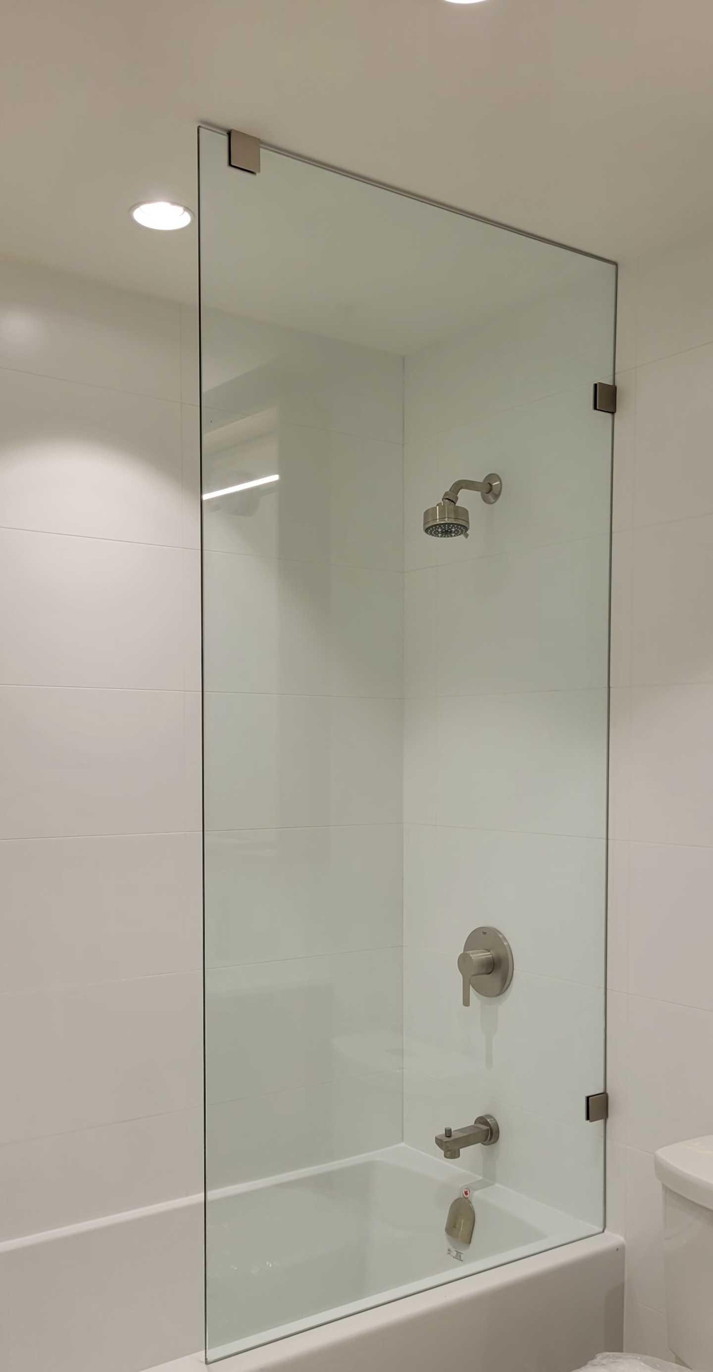 A renovated bathroom, with new bathroom wall tiles, shower glass, and bathtub installed.