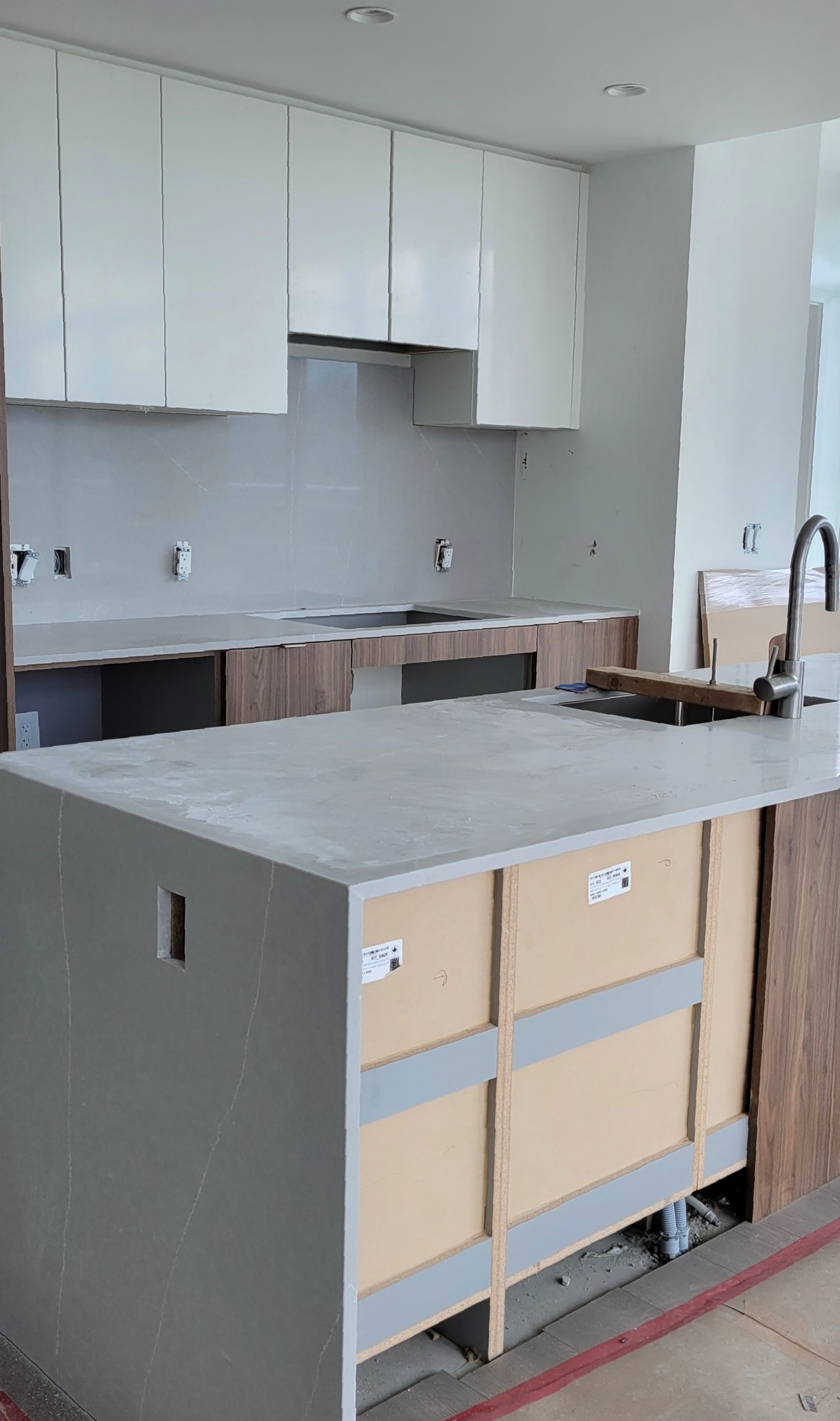 Kitchen renovation with newly-installed marbel kitchen counters, cabinets, and wall tiles.