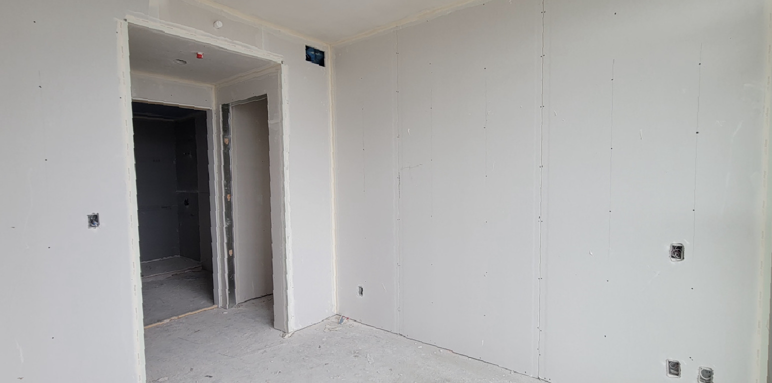 A room under construction, with new installed drywall.