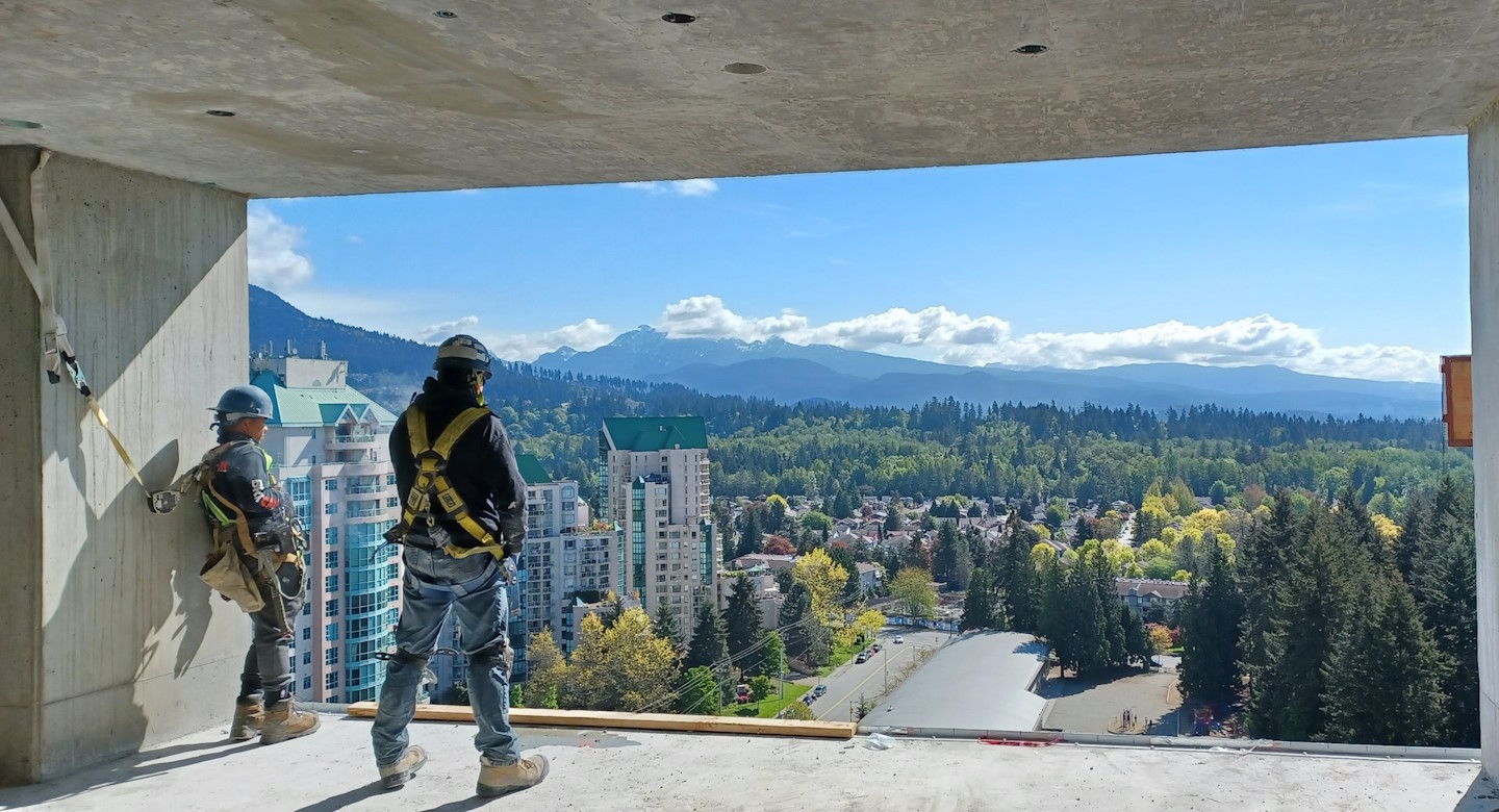 Two construction contractors standing over the city skyline.