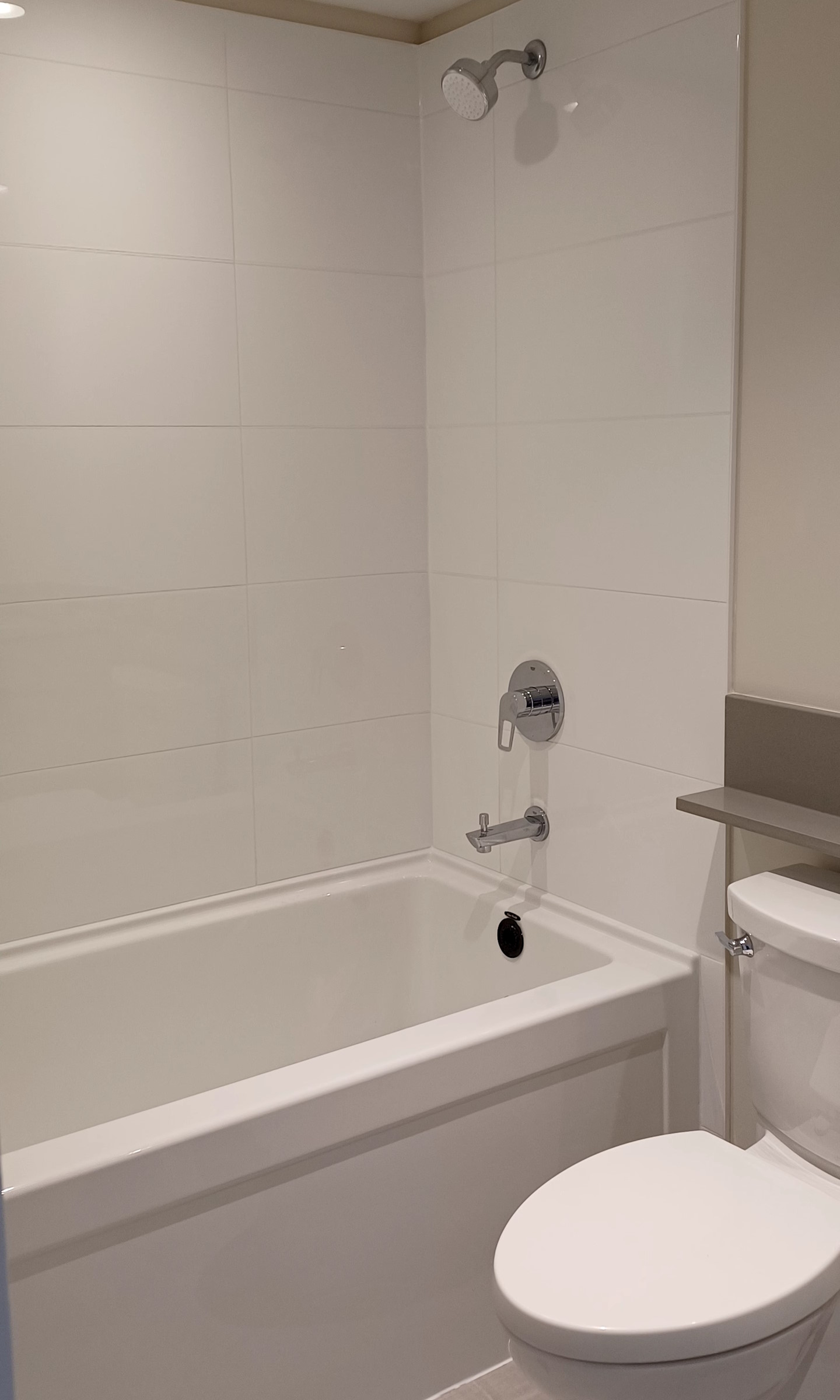 A renovated bathroom, with new bathroom tiles, bathtub, and shower installed.
