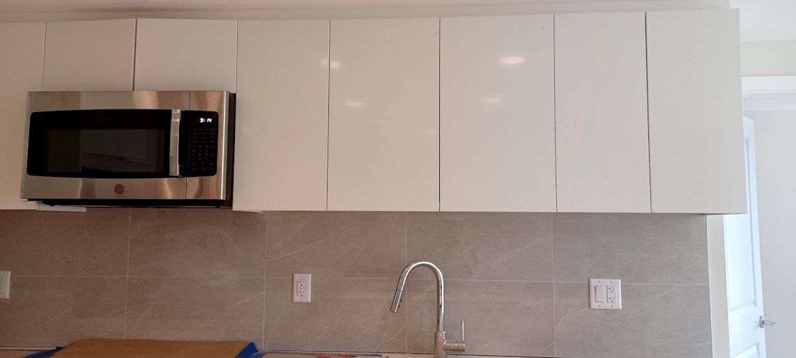 Freshly-installed kitchen wall tiles, with new kitchen cabinets above them.
