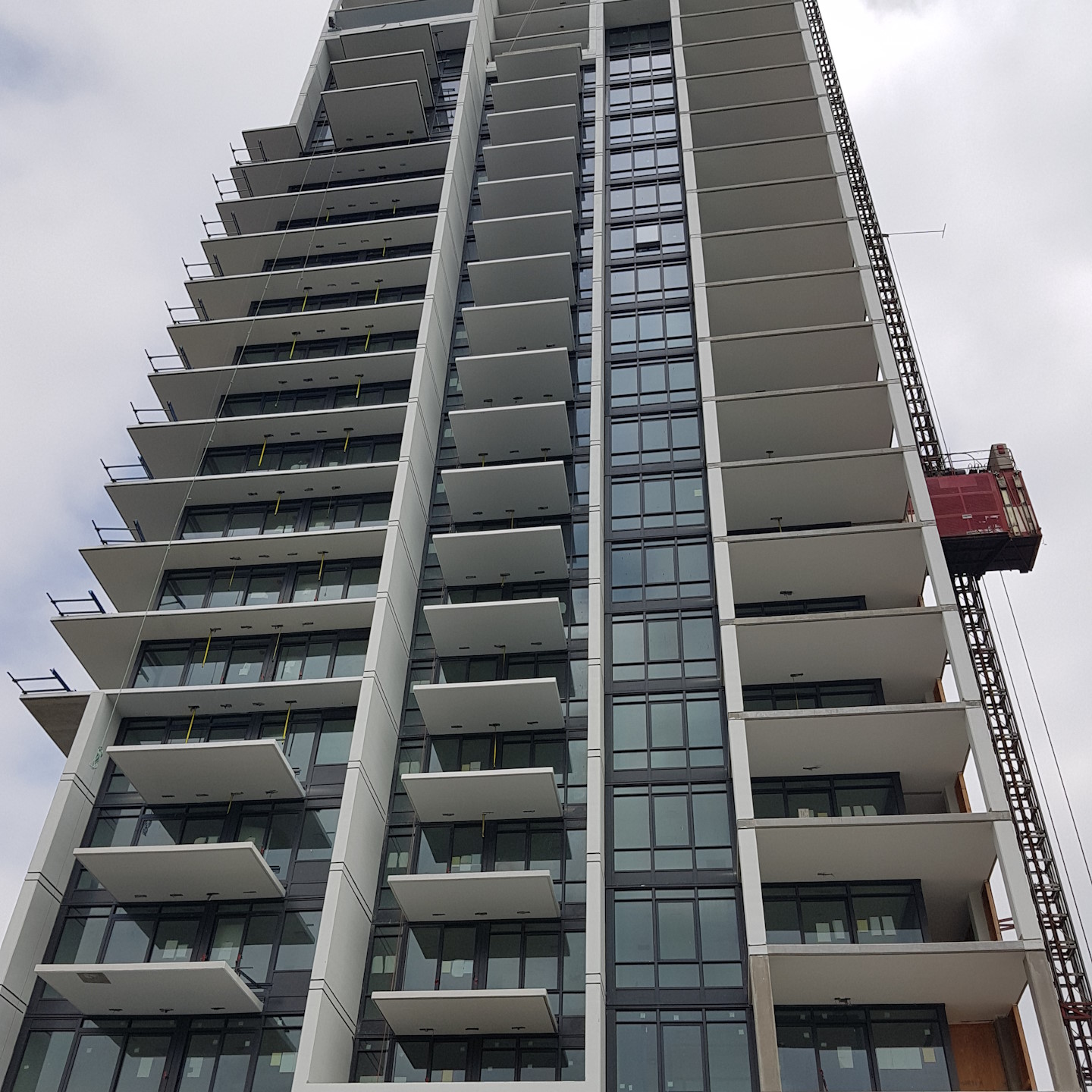 A picture of an apartment complex, taken from the ground, with view of newly-installed windows and glass balcony door.