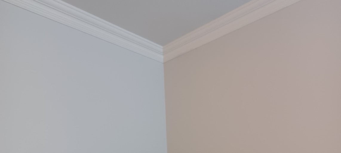 Closeup of painted wall, ceiling, and crown moulding.