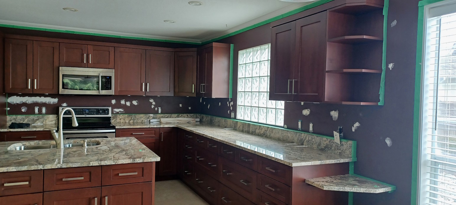 A kitchen under renovation, with patched walls and painter's tape.